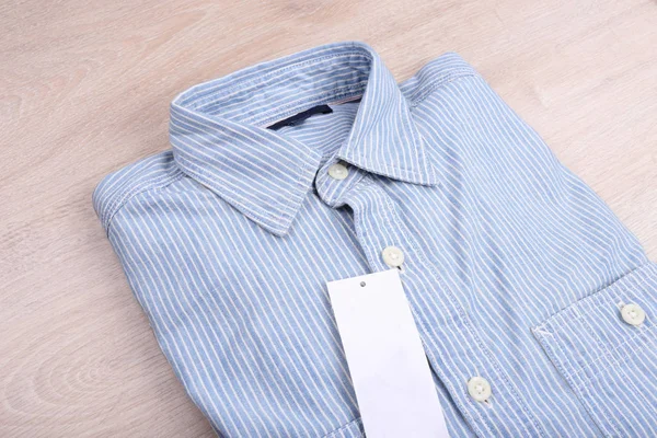 Casual shirt with label on wooden background