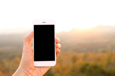 Güneş ışığı ve dağ arka plan ile Smartphone tutan el