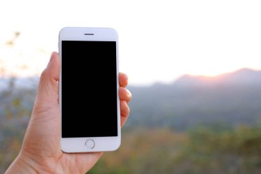 Güneş ışığı ve dağ arka plan ile Smartphone tutan el