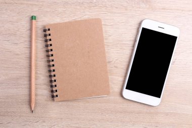 Boş ekran smartphone ile defter ve kalem ahşap backg üzerinde