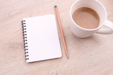 Kahve not defteri ve kalem ahşap arka plan üzerinde