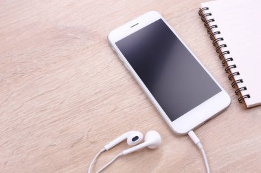 Smartphone mockup ahşap backgro kulaklık ve papre notu ile