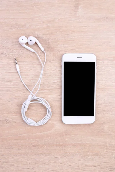 Mockup smartphone com fone de ouvido em fundo de madeira — Fotografia de Stock