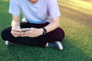 Kullanım smartphone yapay çim üzerinde oturan adam