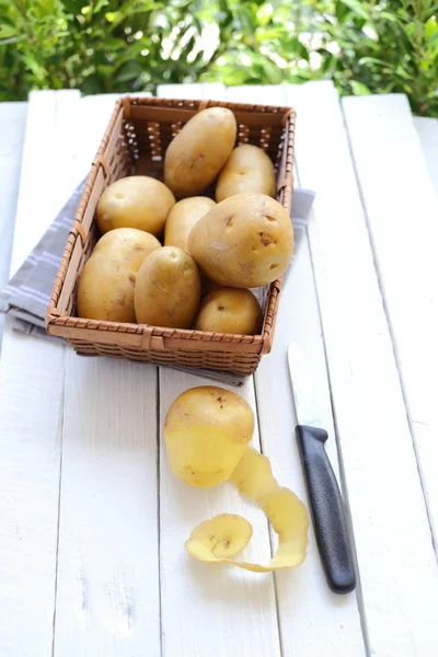 Картофельная кожура и картофель на бамбуковой корзине — стоковое фото