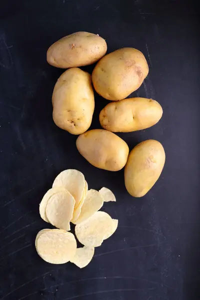 Bramborové lupínky s brambory na černém pozadí — Stock fotografie
