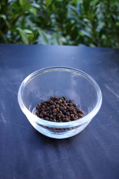 Black pepper in bowl on black background — Stock Photo, Image