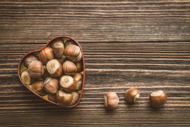 Vintage tarzı ahşap tahta arka plan üzerinde kalp şeklinde teneke kutuda fındık