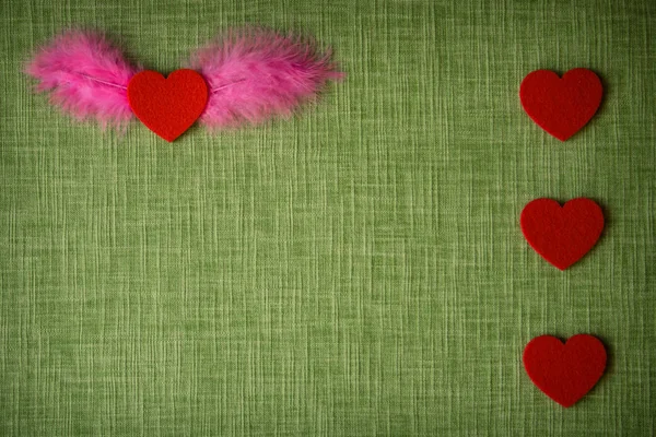 Felt heart and dyed bird feathers on fabric background, Valentine\'s card