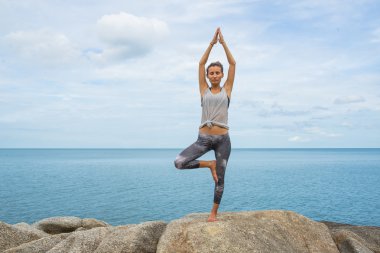 Kız taş yoga ile işgal, bir drenaj Asana, denizde güzel bir manzara bir midilli yogada