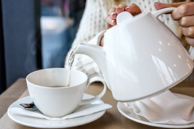 Restoranda sıcak buharlı çay dökülen kadın. Kış eğlence, soğuk hava, içki