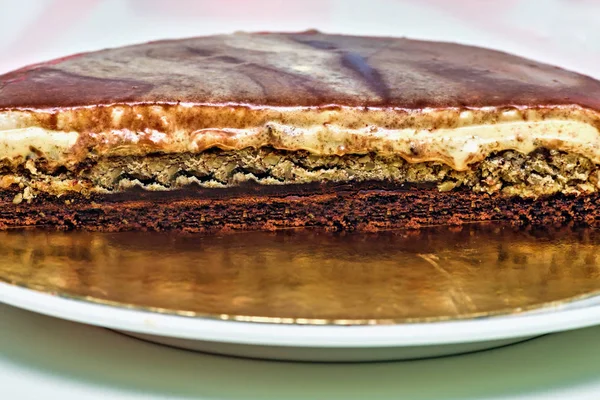 Karamell-Sahnetorte mit Nüssen und Schokoladenschichten. hausgemachtes köstliches Dessert halb in Scheiben geschnitten — Stockfoto