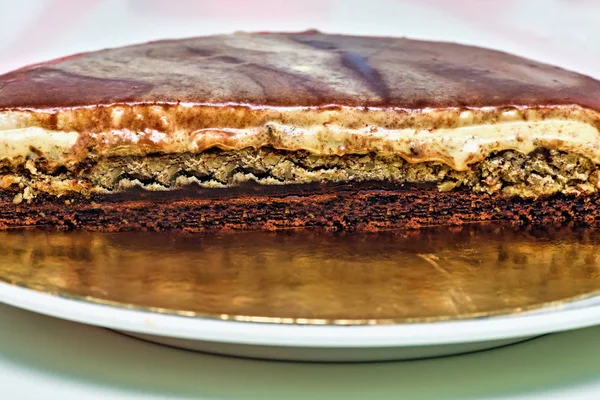 Bolo de creme de caramelo com camadas de nozes e chocolate. Sobremesa deliciosa caseira meio fatiada — Fotografia de Stock