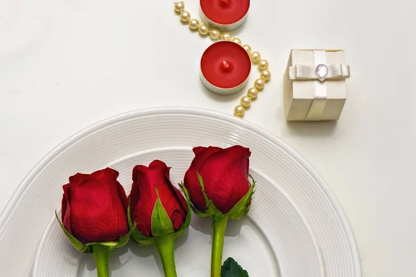 Roses rouges sur une assiette blanche, bougies et coffret cadeau. Composition romantique pour la Saint Valentin, Anniversaire, Événements. Place pour le texte — Photo