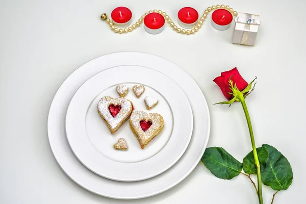 Coração caseiro em forma de biscoitos de amêndoa Linzer na placa branca. Romântico configurar rosas vermelhas e luzes de vela ffor aniversário, casamento, Dia dos Namorados — Fotografia de Stock