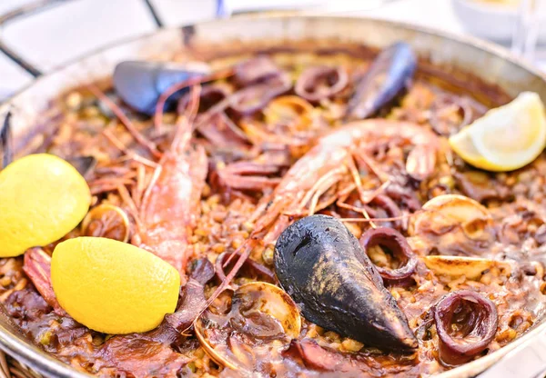 Frutos do mar saborosos Paella em panela preta prato de arroz espanhol tradicional — Fotografia de Stock