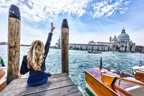 Venedik pier üzerine oturan sarışın kız. Arkadan Görünüm