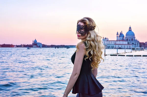 Ritratto di donna dallo sguardo misterioso al tramonto a Venezia. Ragazza con una maschera nera al Canal Grande, Italia — Foto Stock