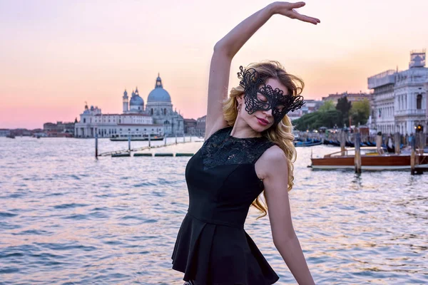 Ritratto di donna dallo sguardo misterioso al tramonto a Venezia. Ragazza che indossa una maschera nera e balla al Canal Grande, Italia — Foto Stock