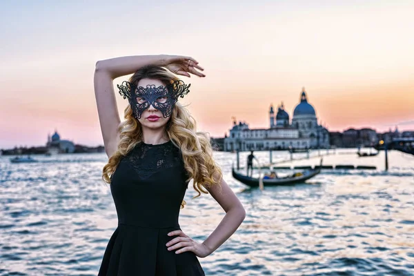 Ritratto di donna dallo sguardo misterioso al tramonto a Venezia. Ragazza con maschera nera e gondola sullo sfondo del Canal Grande, Italia — Foto Stock