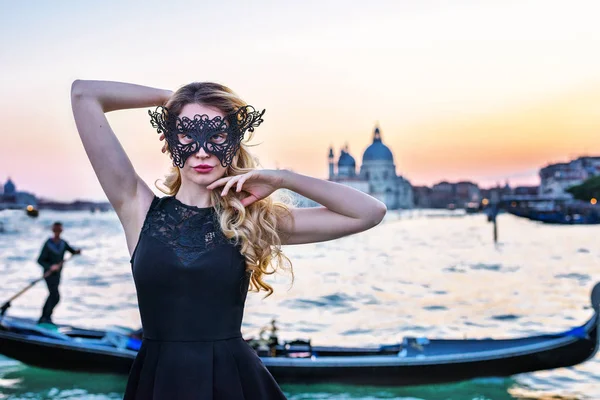 Retrato de una mujer con una mirada misteriosa al atardecer en Venecia. Chica con una máscara negra y una góndola en el fondo del Gran Canal, Italia —  Fotos de Stock