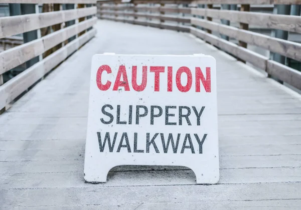 小心滑溜人行道上的警示牌人行道上覆盖着公园里的冰 — 图库照片