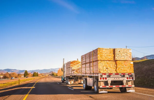 double truck with a lot of wood running on the road when sunset