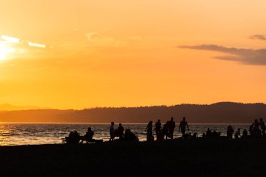 Yazın, Seattle, ABD 'de, gün batımında, plajdaki siluet insanların manzarası..