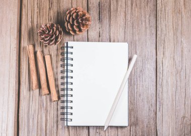 Ahşap tepesinde kalem ve noel süsü olan boş bir defter..