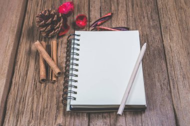 Ahşap tepesinde kalem ve noel süsü olan boş bir defter..