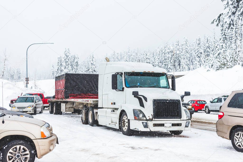 white truck on snow road with traffic jam on snowy day in winter.