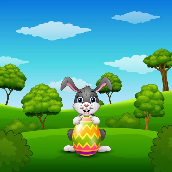 Conejito de dibujos animados sosteniendo huevos de Pascua en el parque — Vector de stock