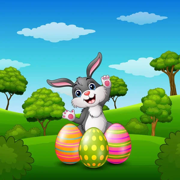 Dibujos animados de conejo feliz con huevos de Pascua en el parque — Vector de stock