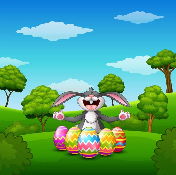 Conejo de dibujos animados riendo con cinco huevos de Pascua decorados en el parque — Vector de stock