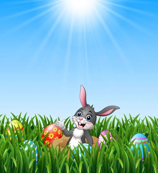 Feliz conejo de Pascua fuera de los agujeros en el suelo con huevos de Pascua en el fondo de hierba — Vector de stock