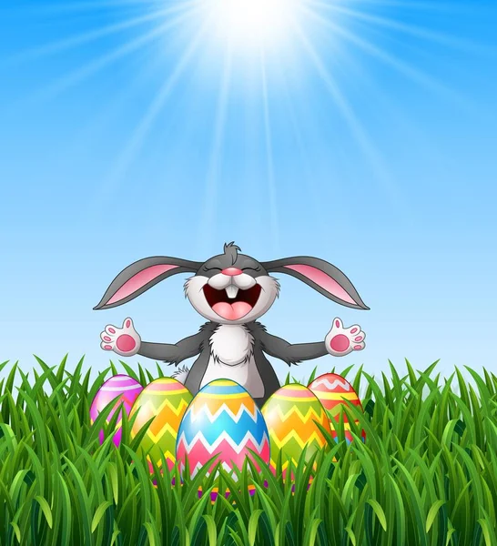 Conejo de dibujos animados riendo con huevos de Pascua en la hierba — Vector de stock