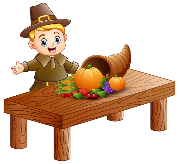 Pilgrim boy with cornucopia of fruits and vegetables on wooden table — Stock Vector