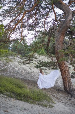 Güzel genç kız büyük bir ağaç altında yürüyor.