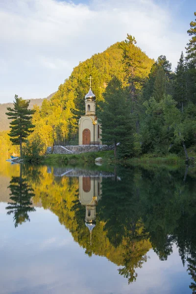 Una pequeña capilla cristiana se encuentra en la orilla del lago del bosque . — Foto de Stock