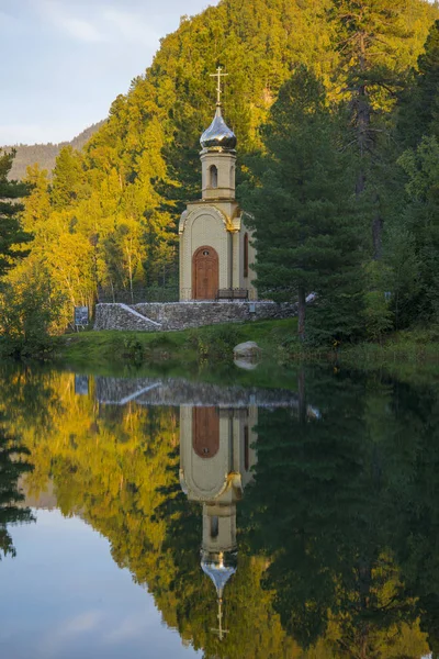 Una pequeña capilla cristiana se encuentra en la orilla del lago del bosque . — Foto de Stock