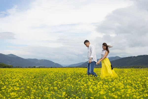 Amantes hombre y mujer caminan en el campo de flores . —  Fotos de Stock
