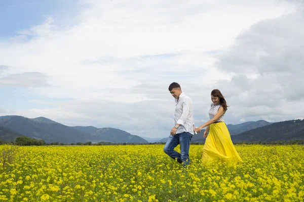 Amoureux homme et femme marchent sur le champ de fleurs . — Photo