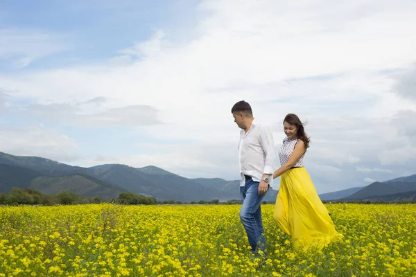 Amantes hombre y mujer caminan en el campo de flores . —  Fotos de Stock