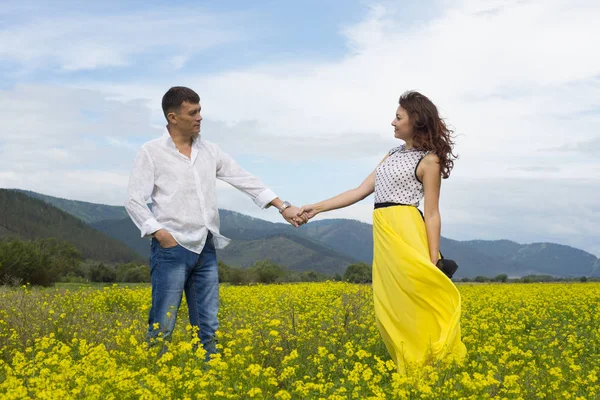 Amantes hombre y mujer caminan en el campo de flores . —  Fotos de Stock