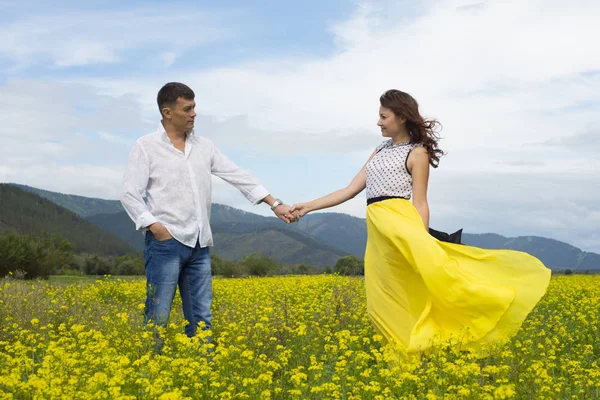 Älskare man och kvinna gå på fältet blomma. — Stockfoto
