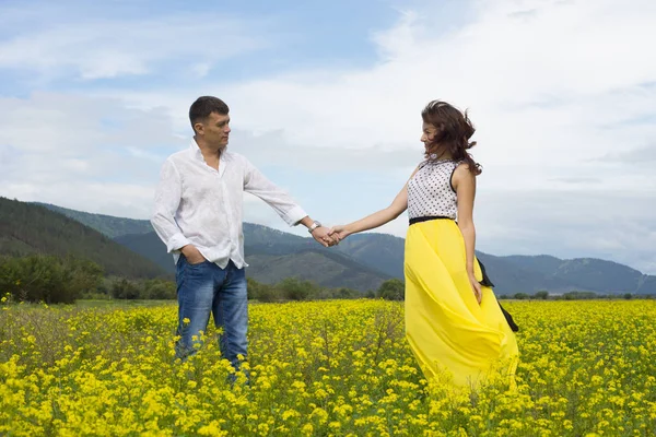 Amantes hombre y mujer caminan en el campo de flores . —  Fotos de Stock