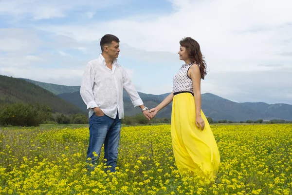 Amantes hombre y mujer caminan en el campo de flores . —  Fotos de Stock