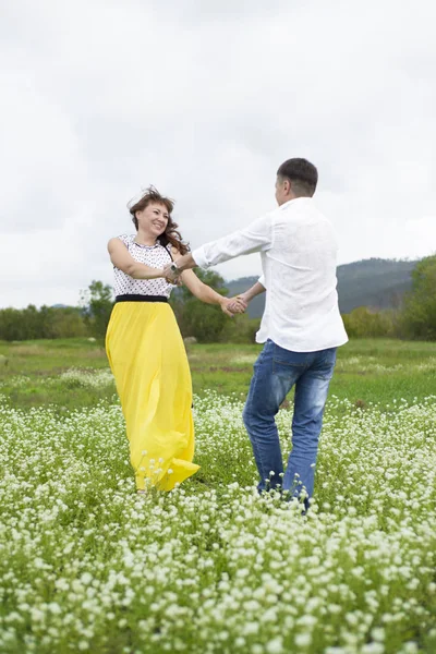 Aşık erkek ve kadın çiçek sahada yürümek. — Stok fotoğraf