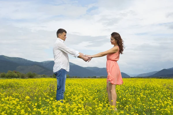 Amantes homem e mulher caminham no campo de flores . Imagem De Stock