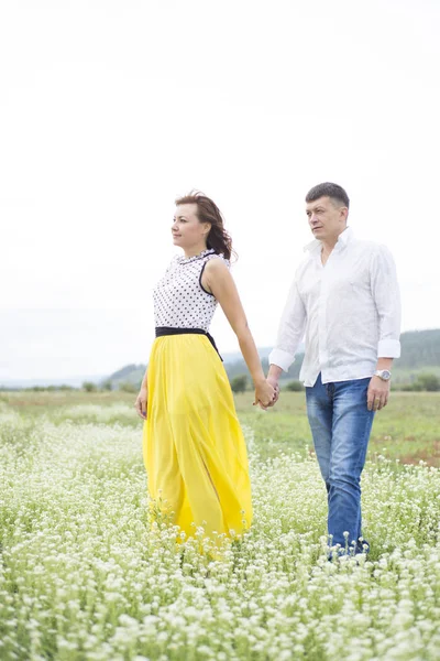 Liefhebbers van man en vrouw lopen op het gebied van de bloem. — Stockfoto